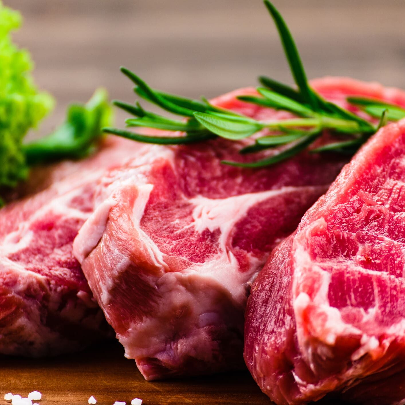 Raw steaks with herbs and lettuce.